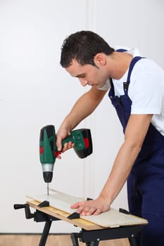Young man working wood on workbench