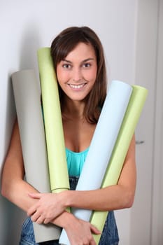 Beautiful young woman holding wallpaper rolls