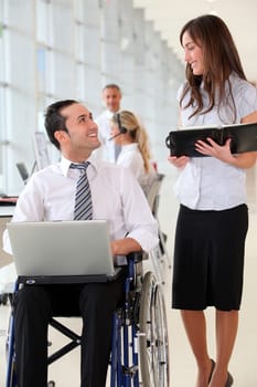 Businessman in wheelchair with assistant in office