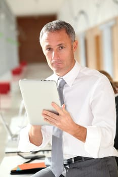 Office worker looking at internet on electronic pad