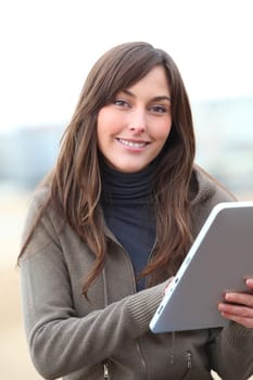 Young woman using electronic pad by the beach in winter