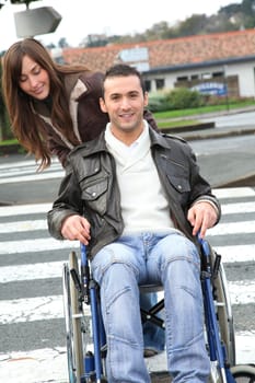 Woman helping friend in wheelchair cross the street
