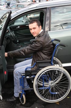 Young man in wheelchair getting in his car