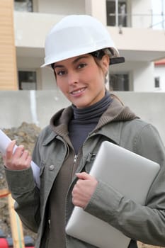 Woman engineer with white security helmet standing on construction site