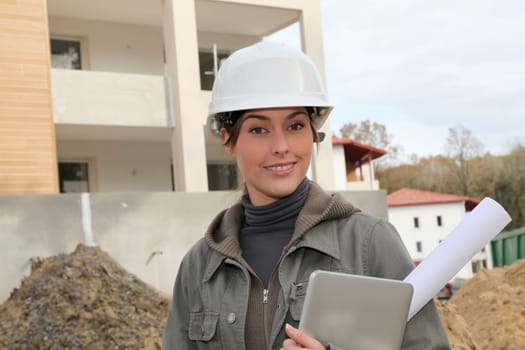 Woman engineer with white security helmet standing on construction site