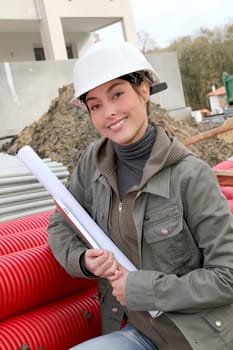 Woman engineer with white security helmet standing on construction site