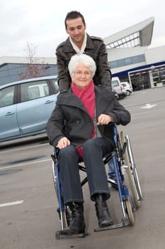 Young man assisting senior woman in wheelchair