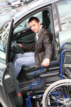 Young man in wheelchair getting in his car