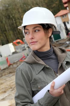 Woman engineer with white security helmet standing on construction site