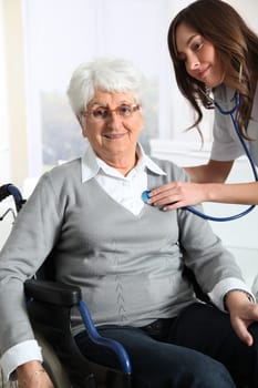 Elderly woman in wheelchair with nurse at home
