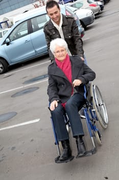 Young man assisting senior woman in wheelchair