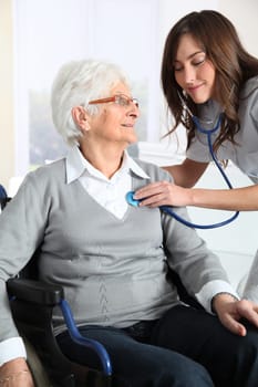 Elderly woman in wheelchair with nurse at home