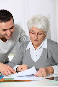 Young man helping elderly woman with paperwork