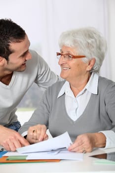 Young man helping elderly woman with paperwork