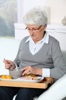 Elderly woman sitting in sofa  with lunch tray