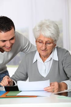 Young man helping elderly woman with paperwork