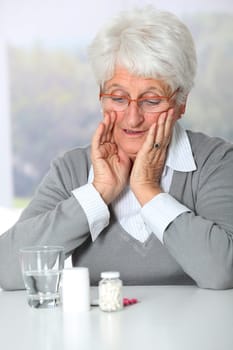 Closeup of old woman looking at medicine bottles