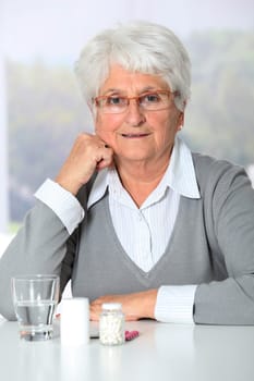 Closeup of old woman looking at medicine bottles