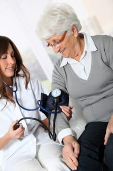 Closeup of nurse checking senior woman blood pressure