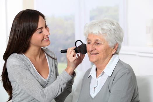 Young woman helping old woman to put makeup on