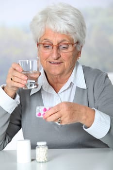 Closeup of old woman looking at medicine bottles