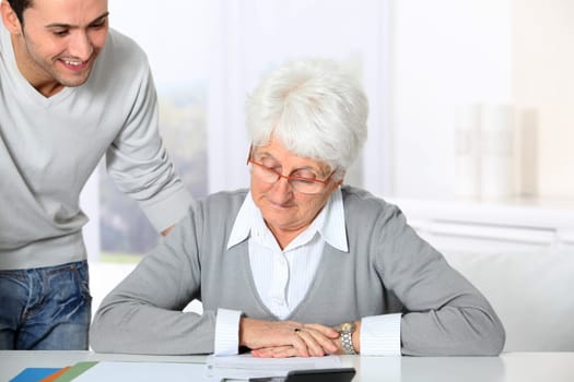 Young man helping elderly woman with paperwork