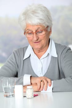 Closeup of old woman looking at medicine bottles