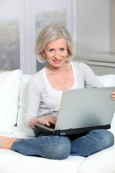 Senior woman sitting in sofa with laptop computer