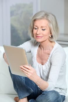 Closeup of senior woman sitting on sofa with electronic pad