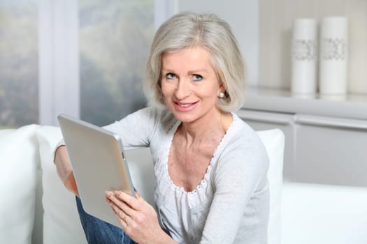 Closeup of senior woman sitting on sofa with electronic pad