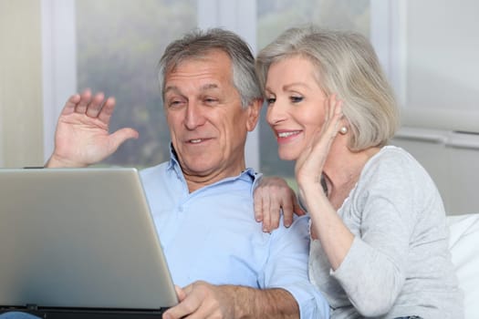 Senior couple waving at web camera