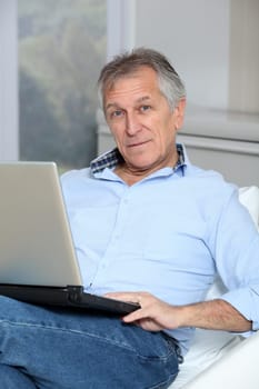 Senior man in sofa with laptop computer