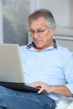 Senior man in sofa with laptop computer