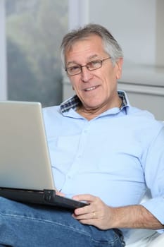 Senior man in sofa with laptop computer