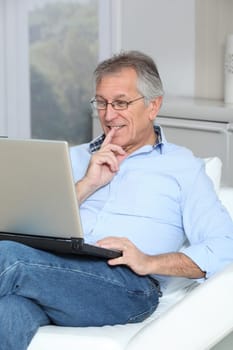 Senior man in sofa with laptop computer