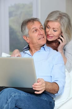 Senior couple at home surfing on internet