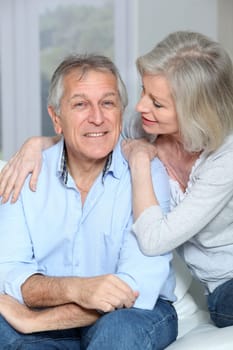 Portrait of happy senior couple sitting in sofa