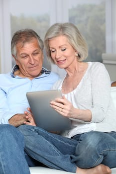 Senior couple surfing on internet with electronic tablet