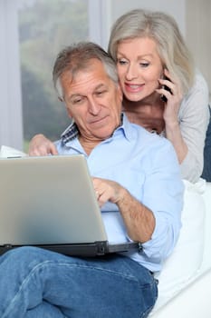 Senior couple at home surfing on internet