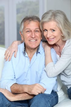 Portrait of happy senior couple sitting in sofa