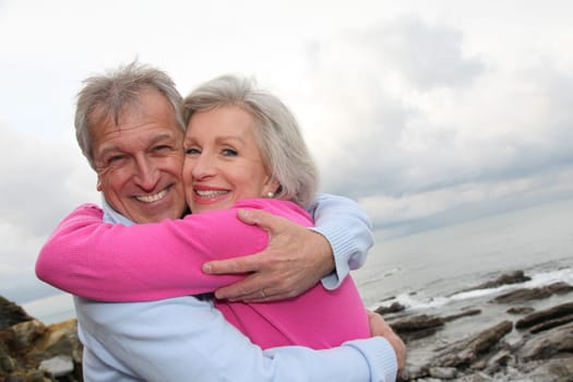 Happy senior couple embracing each other by the sea