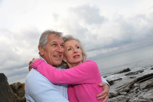 Happy senior couple embracing each other by the sea