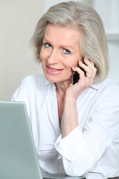 Senior businesswoman in the office talking on the phone
