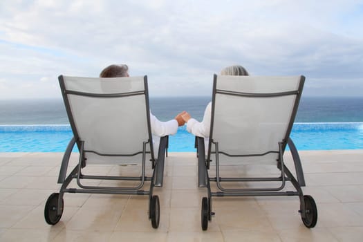 Senior couple relaxing in long chairs