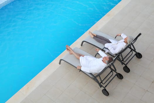 Senior couple relaxing in long chairs