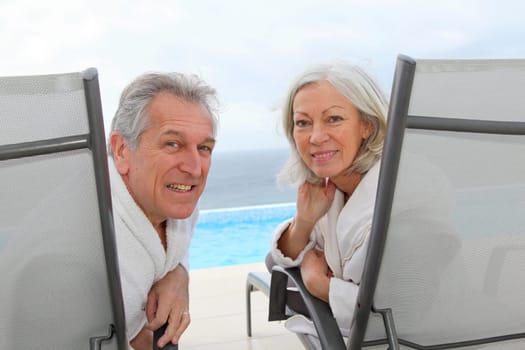 Senior couple relaxing in long chairs