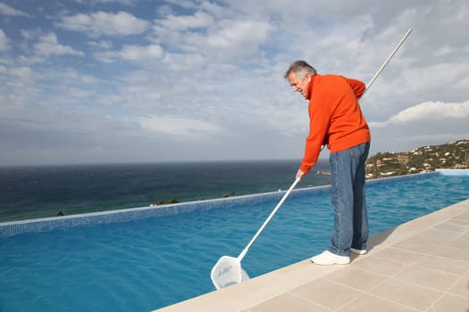 Senior couple cleaning swimming pool
