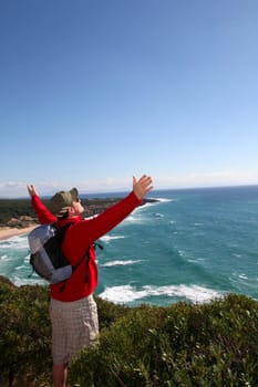 Hiker stretching arms up in front of the sea