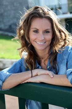 Beautiful woman standing against home fence
