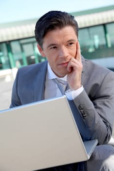 Businessman working on laptop computer by the airport